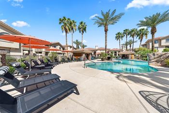 A pool surrounded by palm trees and sun loungers.